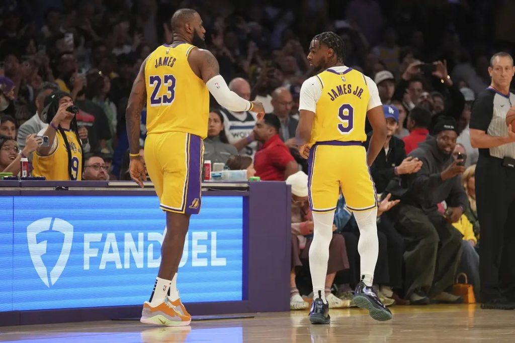 El delantero de Los Angeles Lakers, LeBron James (23), y la escolta Bronny James (9) están en la cancha durante la primera mitad de un partido de baloncesto de la NBA contra Minnesota.